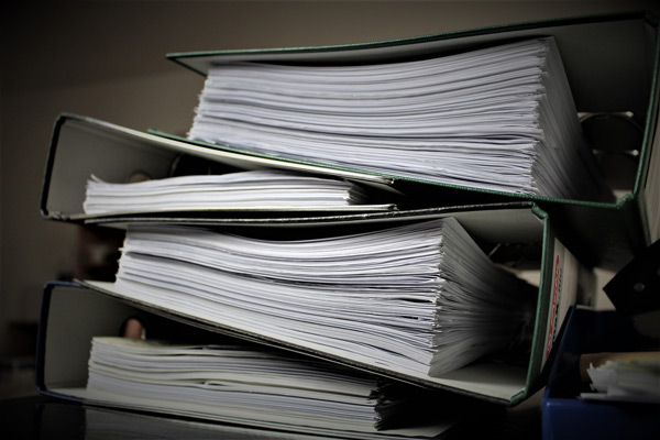 pile of binders with paper work. learn about 3. Business Continuity, Disaster Planning, Business Interruption with HardeRisk